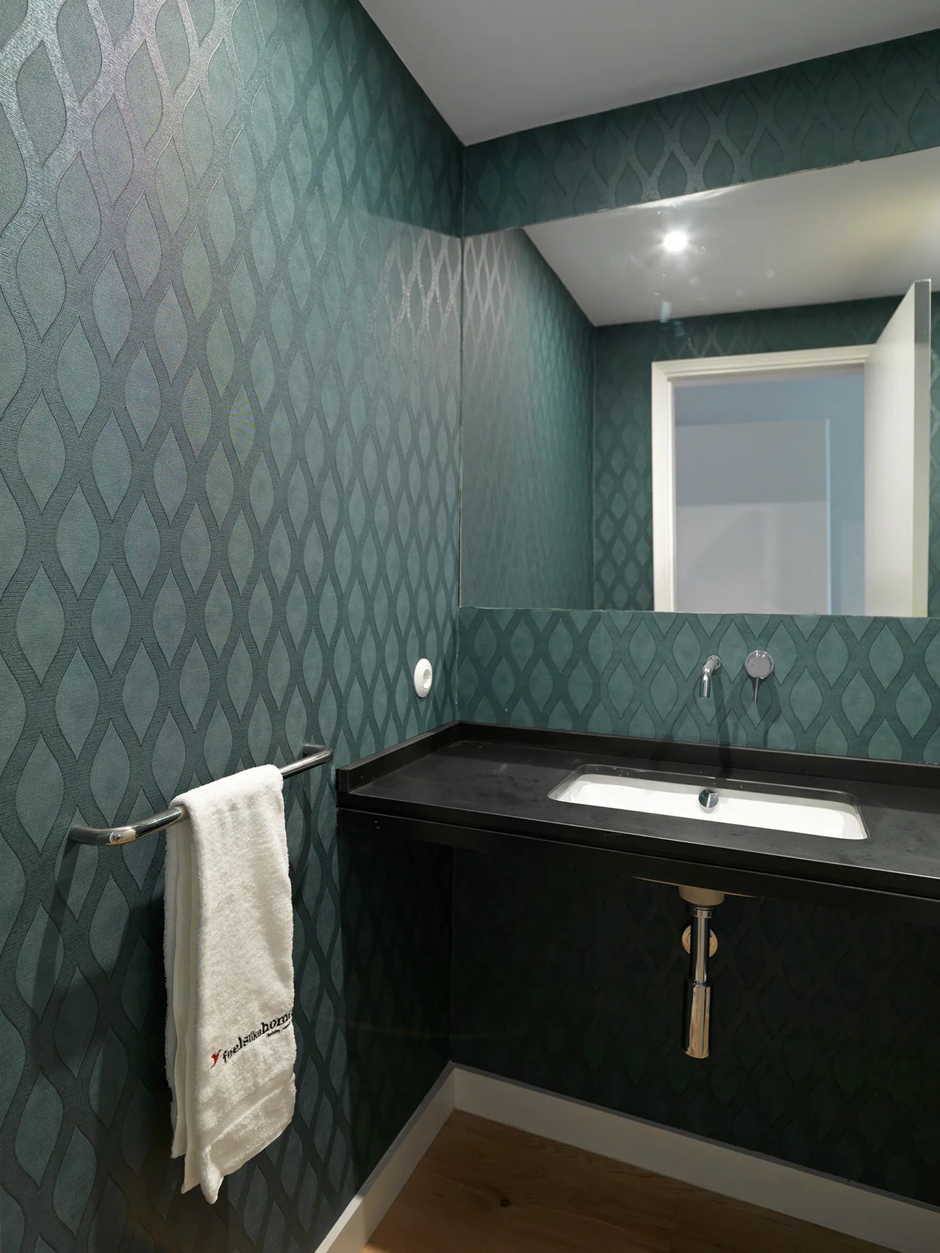 A bathroom with a dark vanity, white sink, and patterned walls.