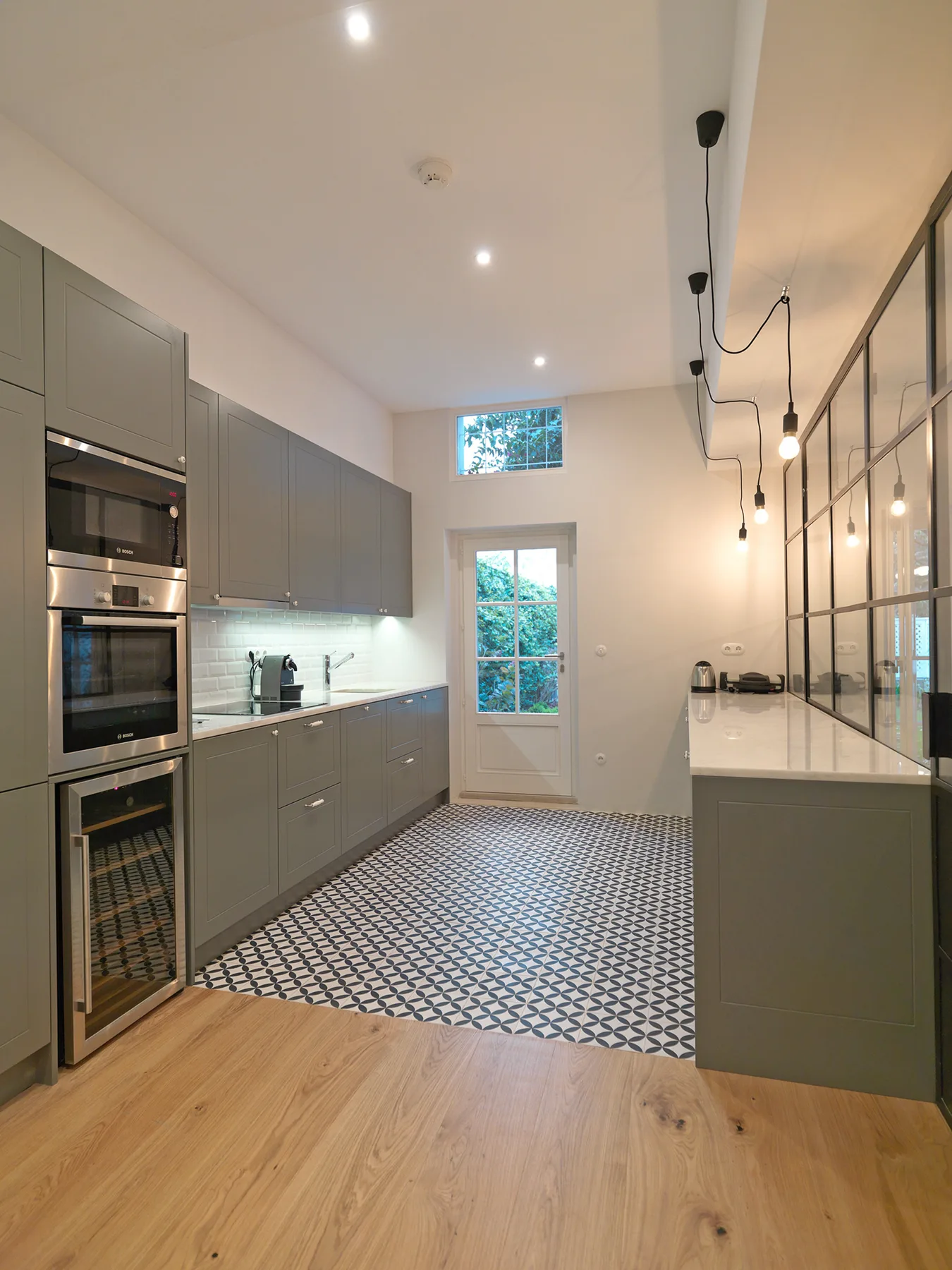 A modern kitchen with gray cabinetry, a tiled floor, and a long island.