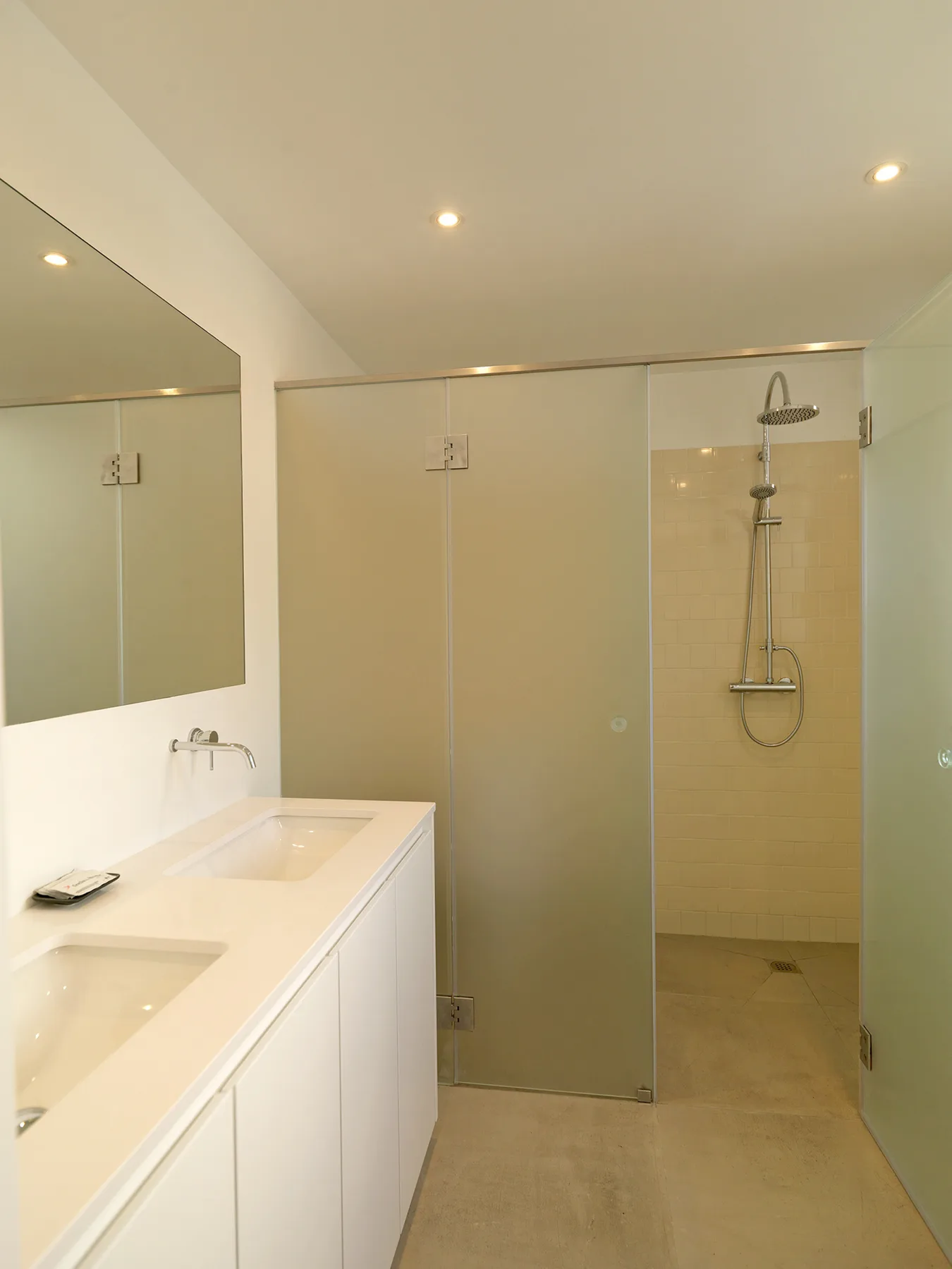 A modern bathroom with a long vanity and a glass-enclosed shower.
