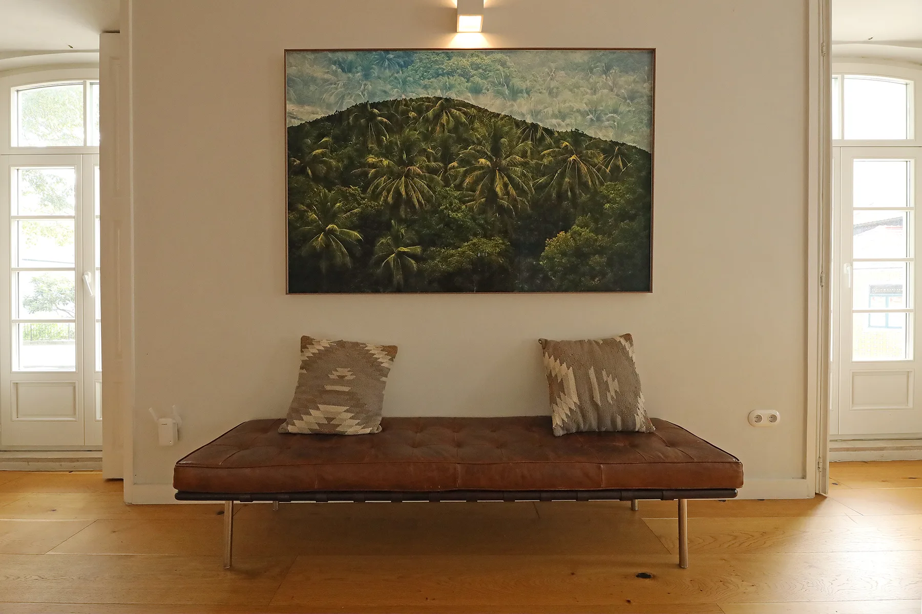 A seating area with a low bench beneath a landscape painting.