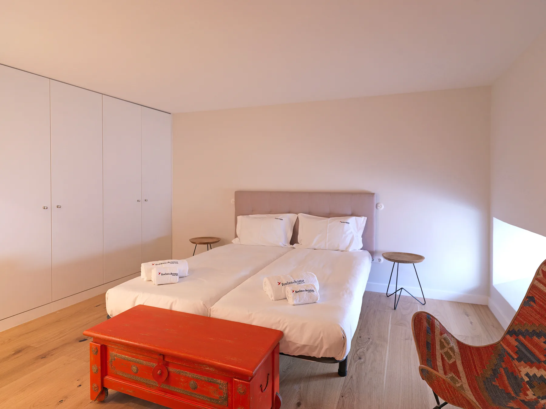 A bedroom with a bed, white bedding, and a red chest.