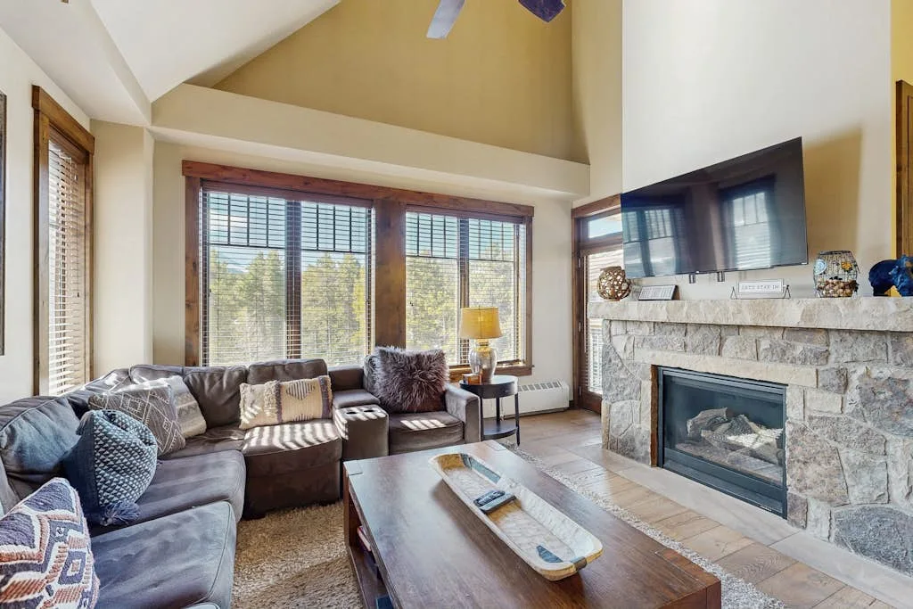 A living room with seating arranged around a coffee table and fireplace.