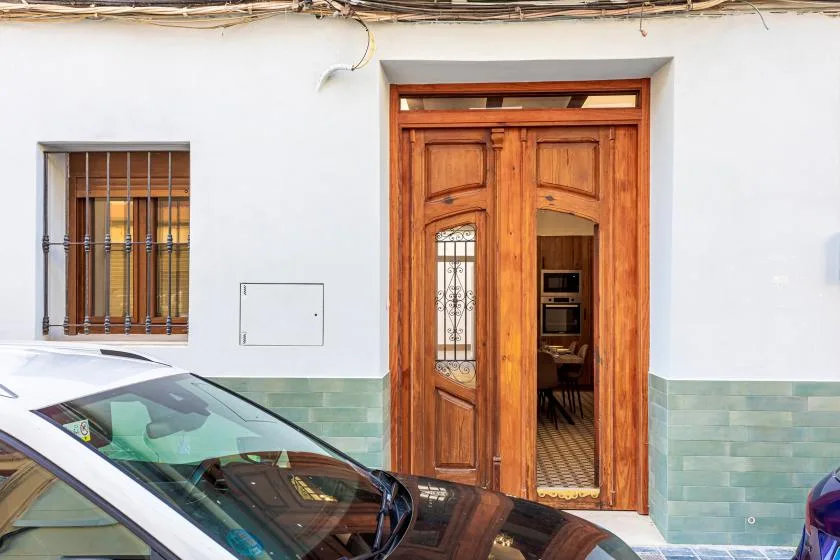 A wooden entrance door and barred window on a white exterior wall.