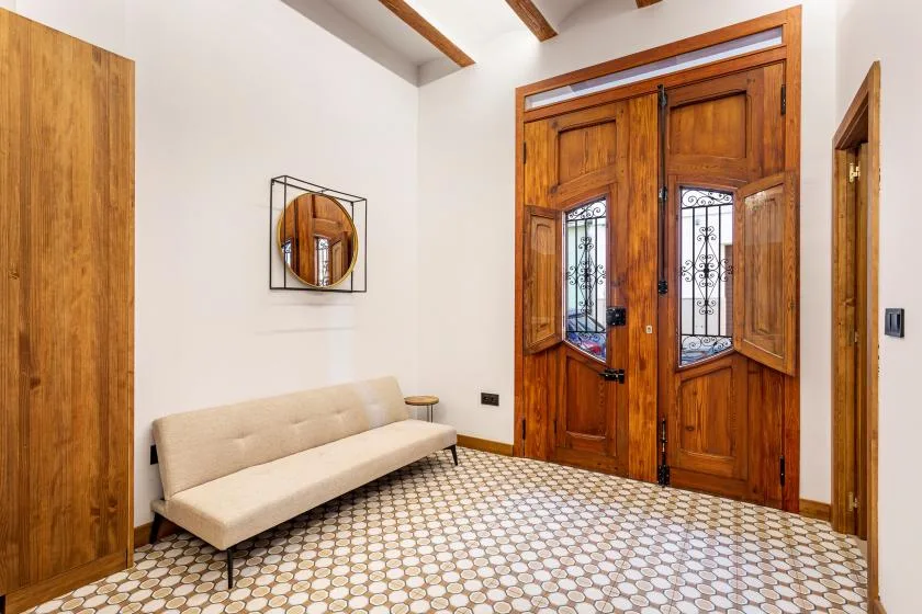 An entryway with wooden doors, a bench, and patterned tile flooring.