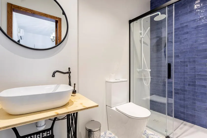 A bathroom with a vessel sink, toilet, and glass-enclosed shower.