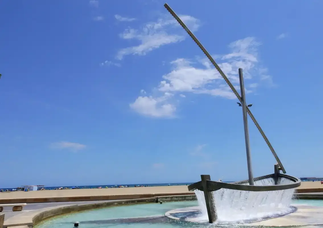 A shallow pool beside a sandy beach under a blue sky.