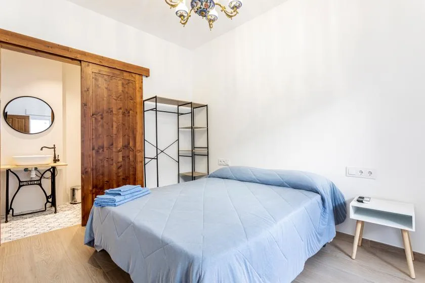 A bedroom with a bed covered in a light blue quilt.
