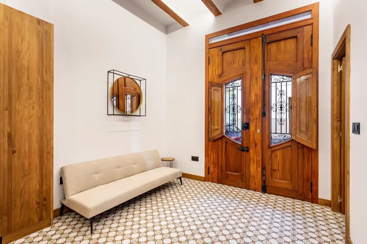 An entryway with wooden double doors and a beige bench.