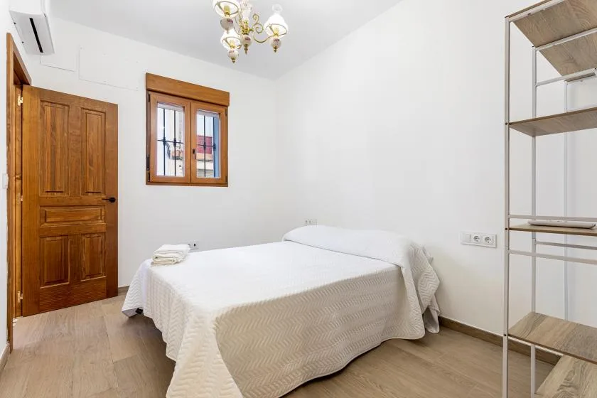 A bedroom with a double bed, wooden door, and window.