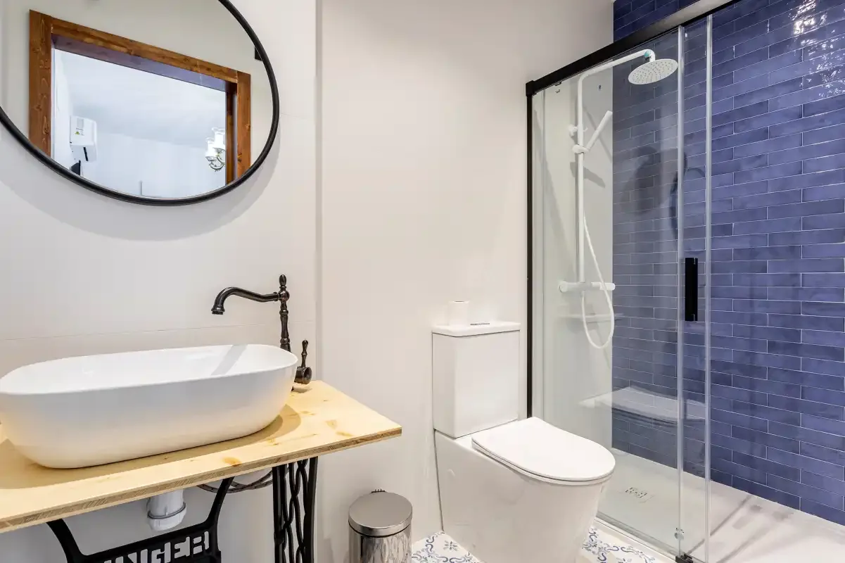 A bathroom with a vessel sink, toilet, and glass-enclosed shower.