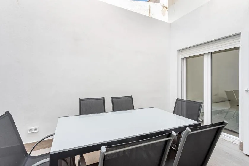 A dining area with a large table and several chairs beside sliding glass doors.