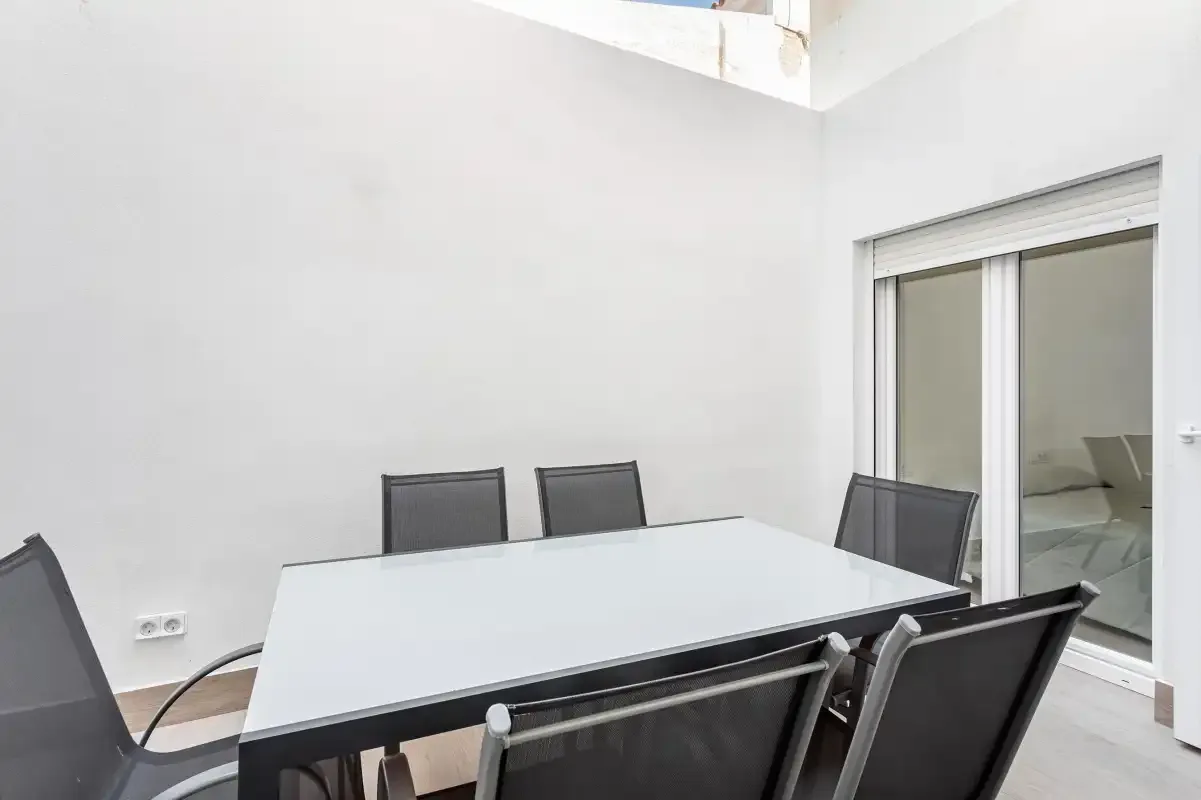 A dining area with a rectangular table and dark seating beside sliding glass doors.