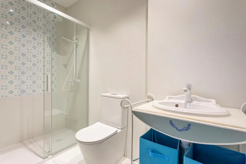 A bathroom with a glass shower, toilet, and sink.