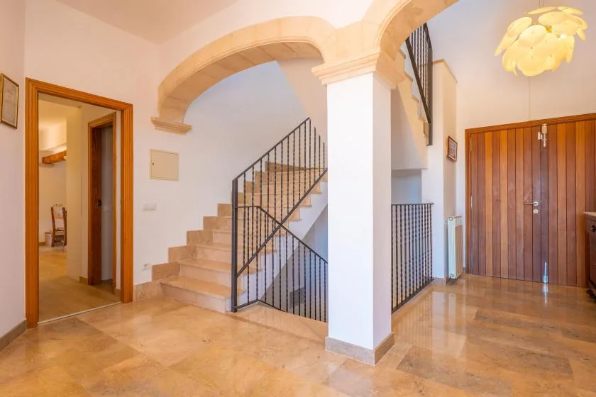 An interior entry hall with a staircase and a wooden door.