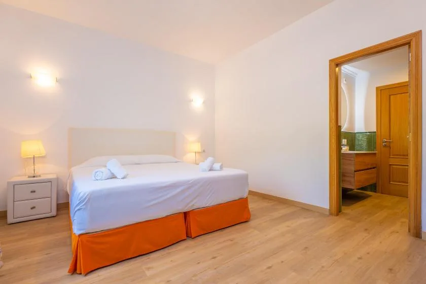 A bedroom with a neatly made bed and a doorway opening to an adjoining room.