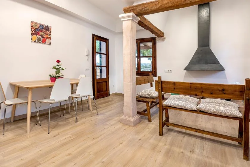 A bright dining and sitting area with a wooden table and bench seating.