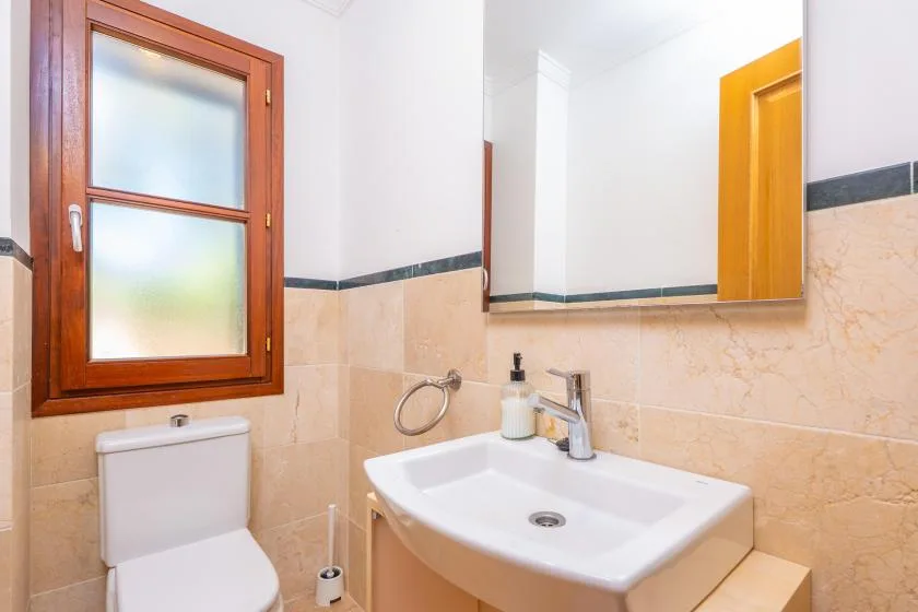 A bathroom with a sink, toilet, and frosted window.