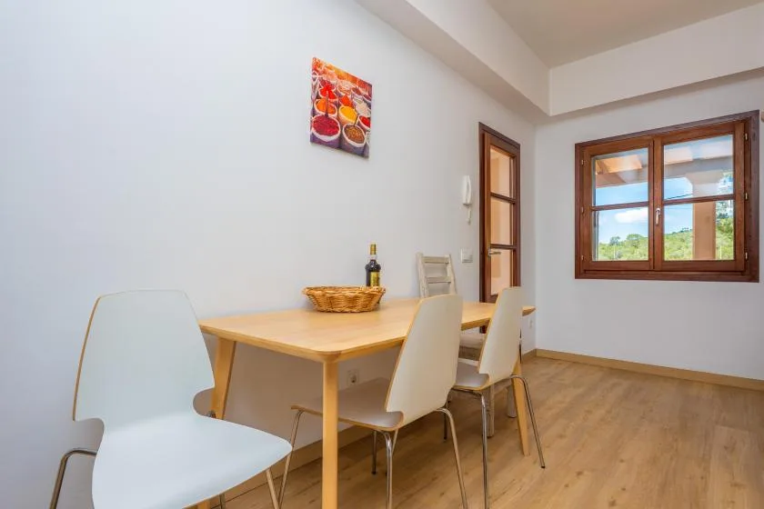 A dining area with a wooden table and chairs beside a window.