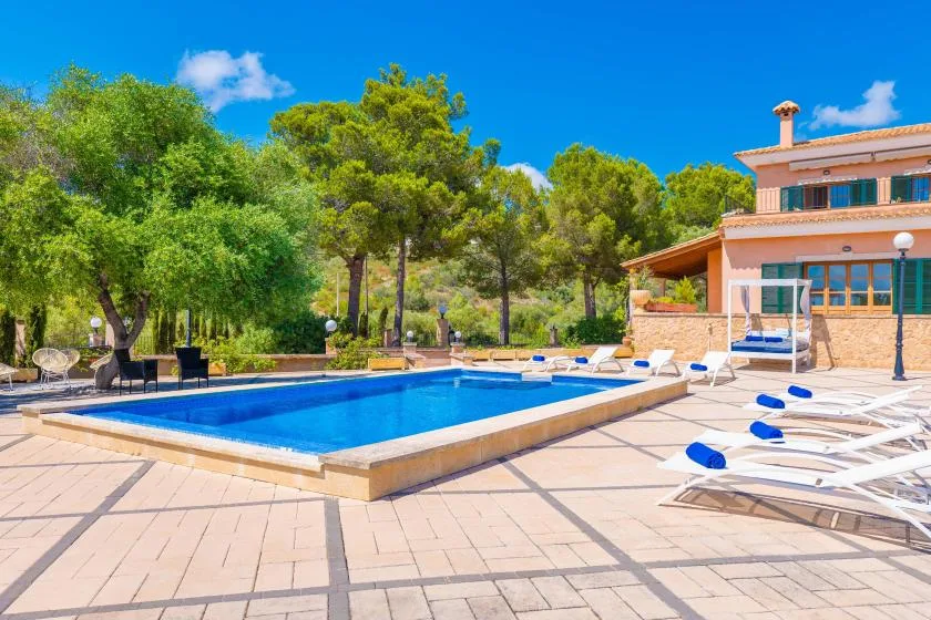 An outdoor swimming pool beside a paved patio and a house.