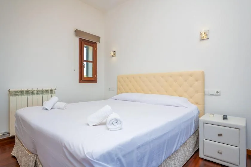 A bedroom with a neatly made bed and a small bedside cabinet.