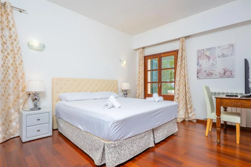A bedroom with a neatly made bed, bedside tables, and a window.