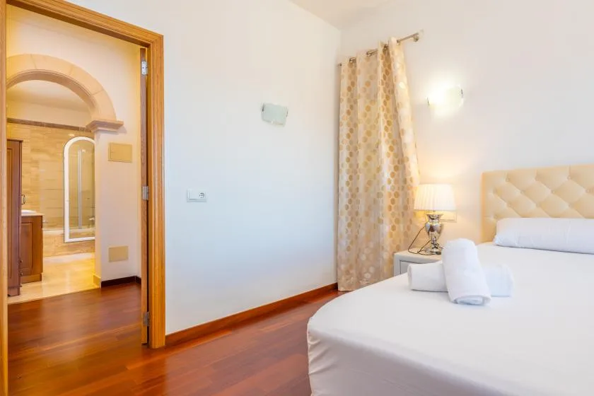 A bedroom with a neatly made bed and patterned curtains.