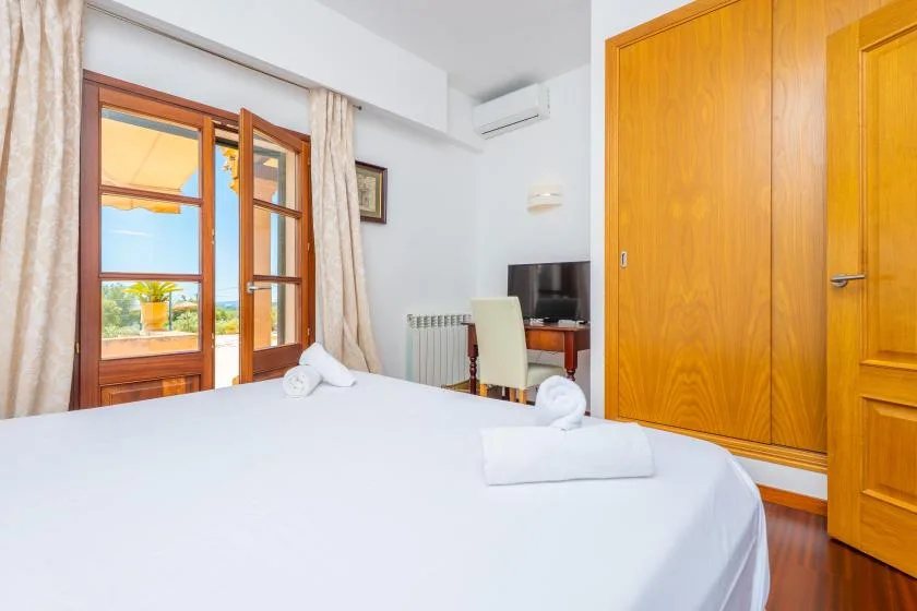 A bright bedroom with a neatly made bed and wooden doors.