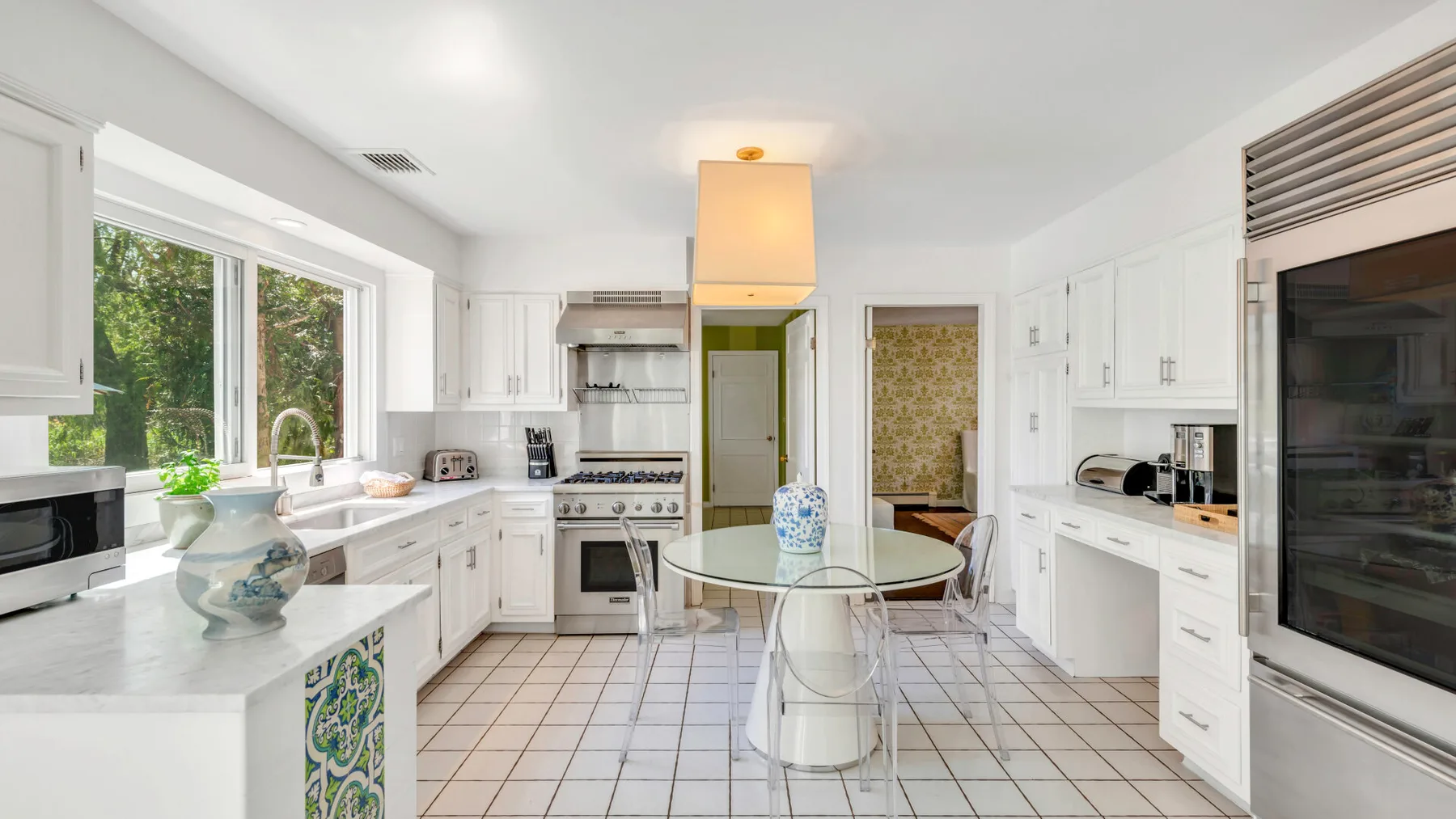 Una cocina luminosa con gabinetes blancos, una isla central y ventanas grandes.