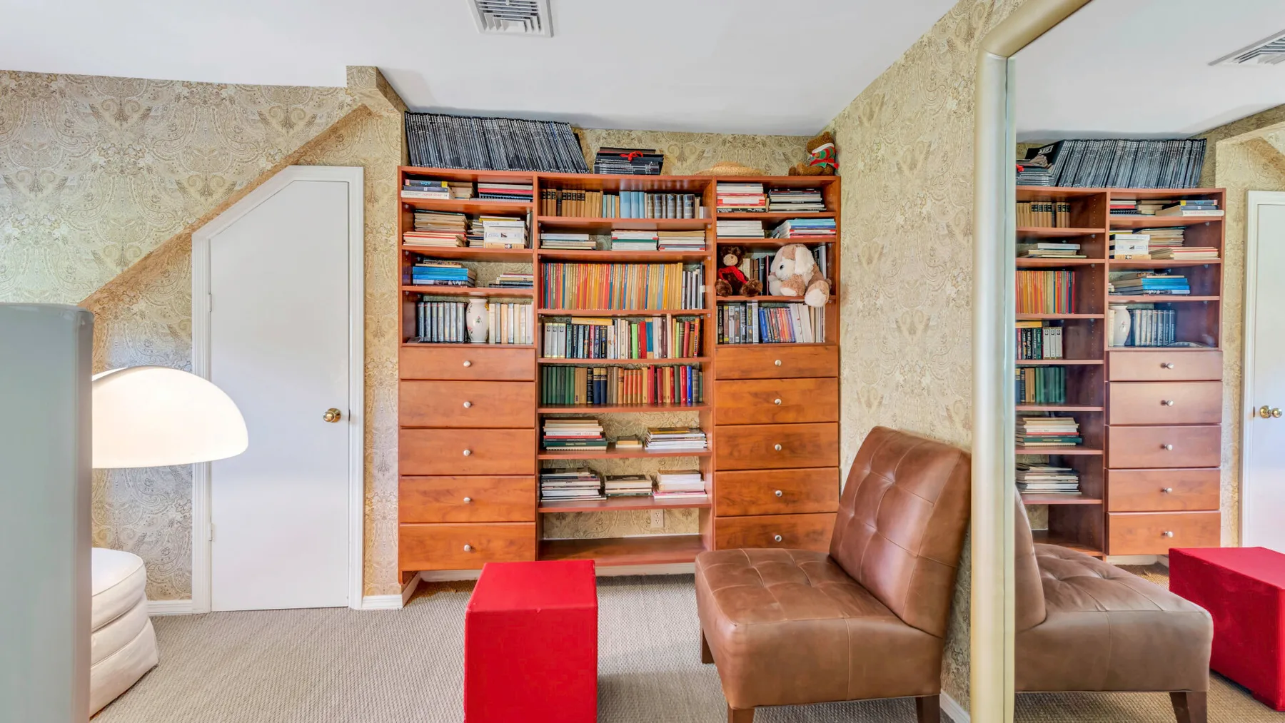 Una sala de estar con una gran estantería de madera y asientos marrones.