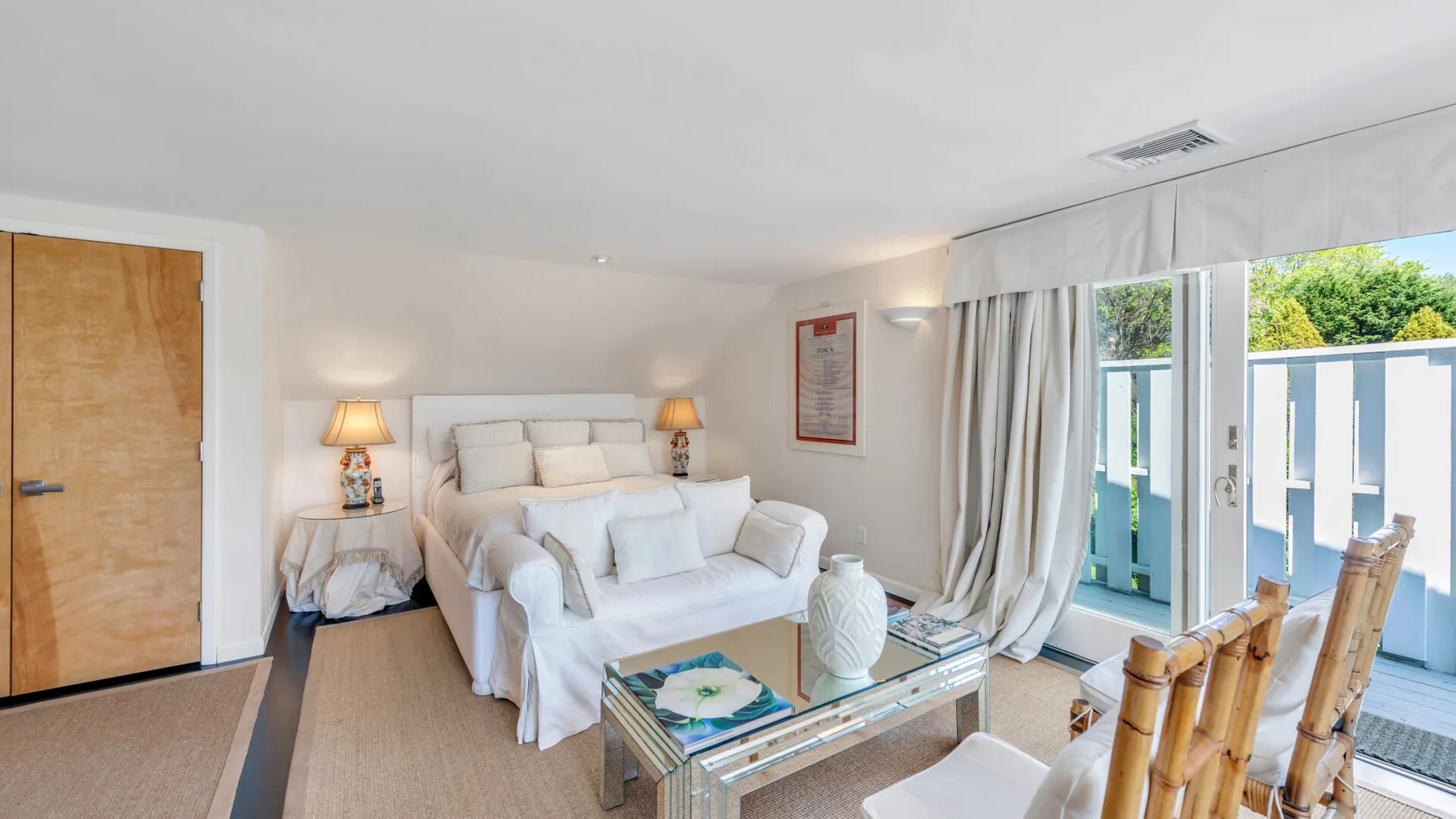 Una sala luminosa con asientos blancos junto a grandes puertas de vidrio.