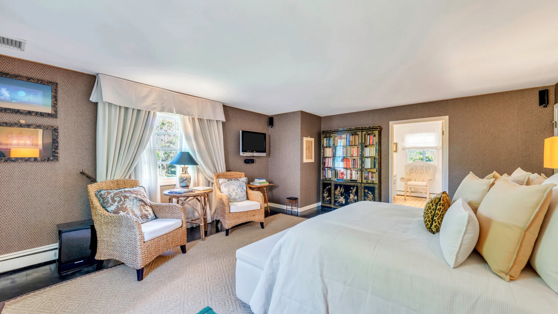 Un dormitorio con una cama bien tendida y una zona de estar junto a la ventana.