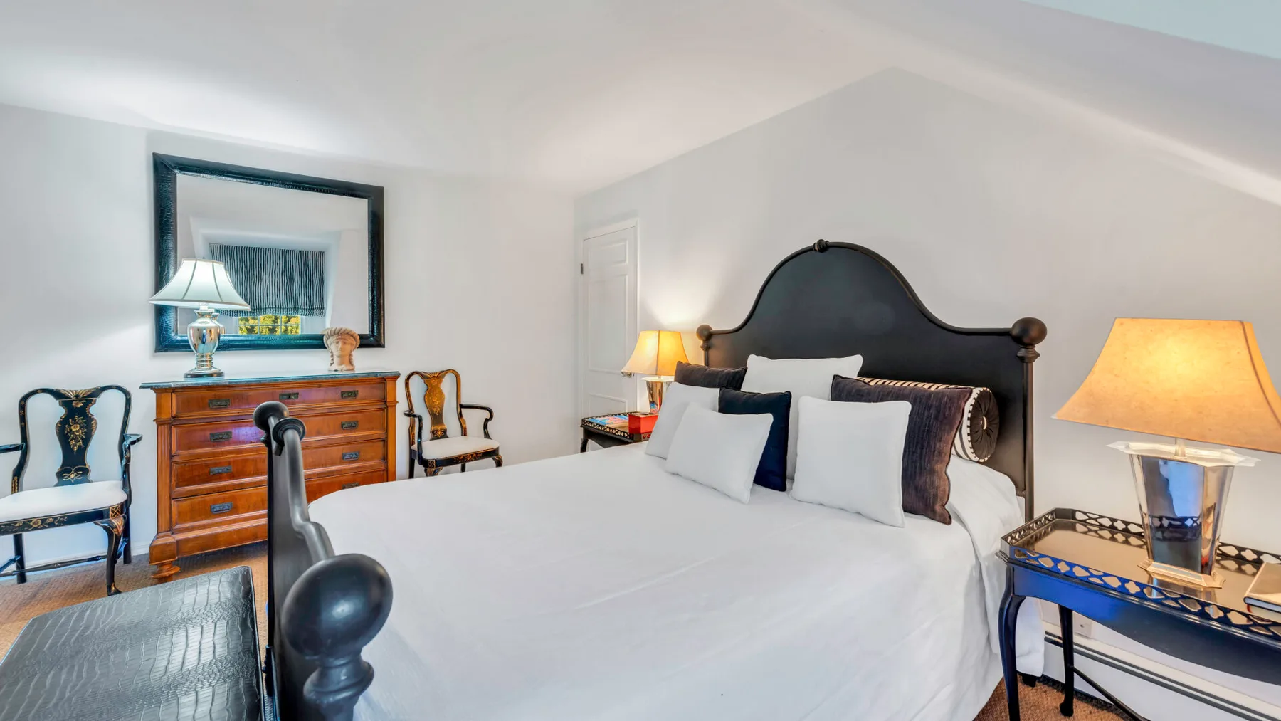 Un dormitorio con una cama bien tendida y una cómoda de madera.