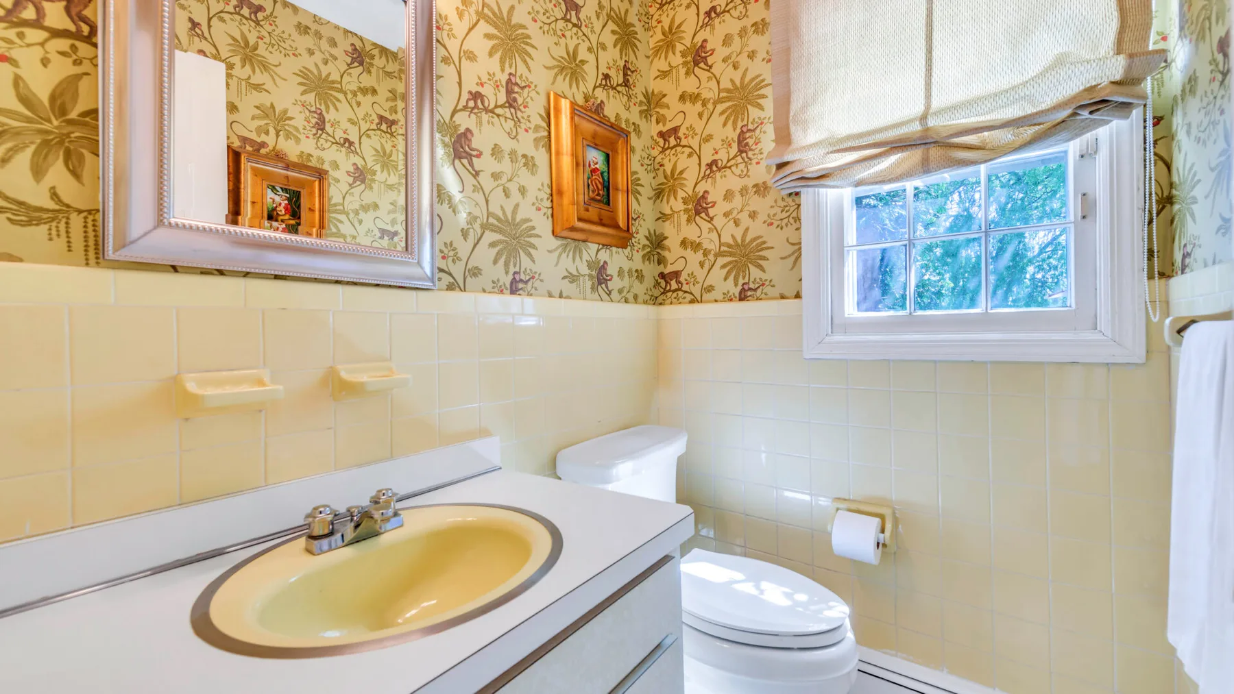 Un baño con lavabo, inodoro y papel tapiz estampado.