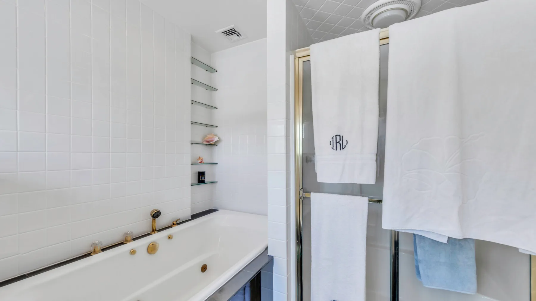 Un baño alicatado con bañera y toallas colgadas al lado.