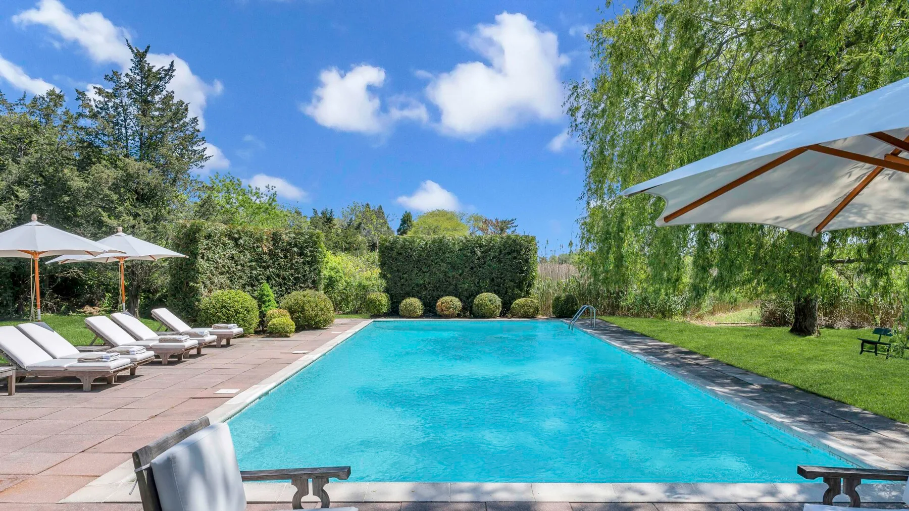 Una piscina al aire libre está rodeada de asientos y vegetación frondosa.