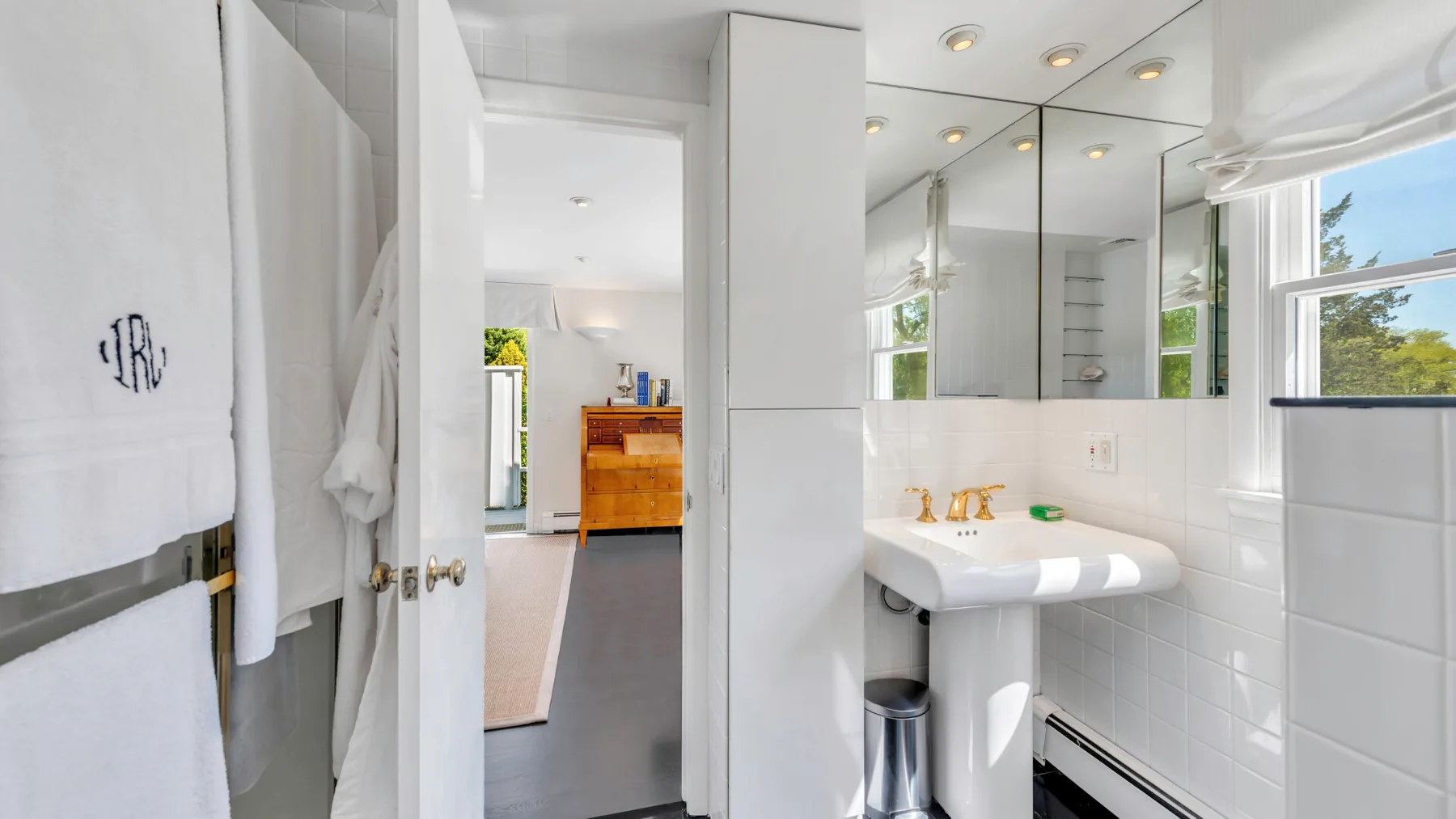 Un baño luminoso con un lavabo blanco y paredes con espejos.