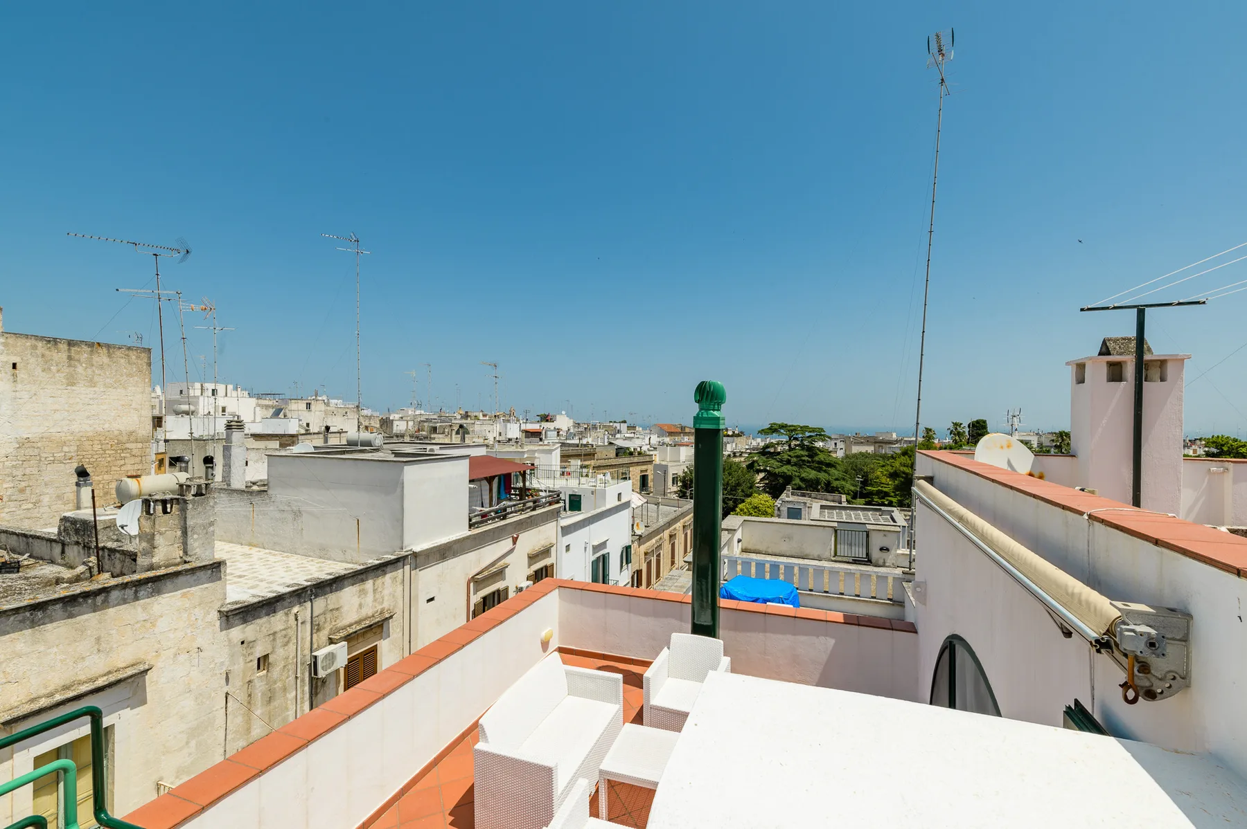 Una terraza en la azotea ofrece vistas de los edificios cercanos bajo un cielo azul despejado.