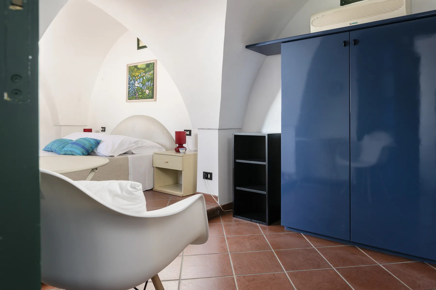 Un dormitorio con una cama, asientos blancos y un armario azul.