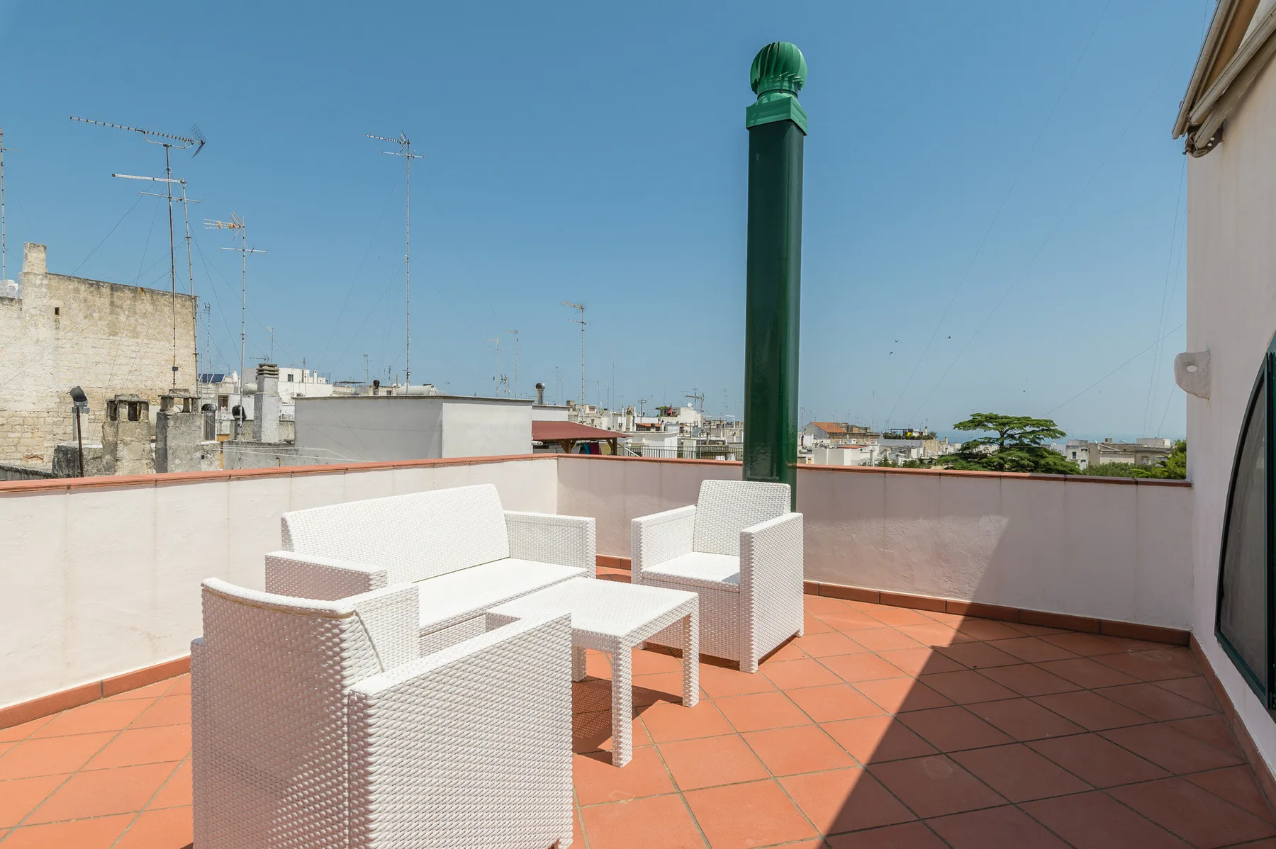 Una terraza en la azotea con asientos blancos y una mesa pequeña.