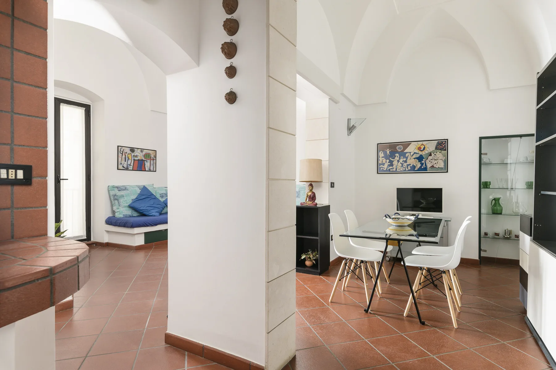 Un comedor y sala luminosos con una mesa, sillas y un pequeño rincón de descanso.