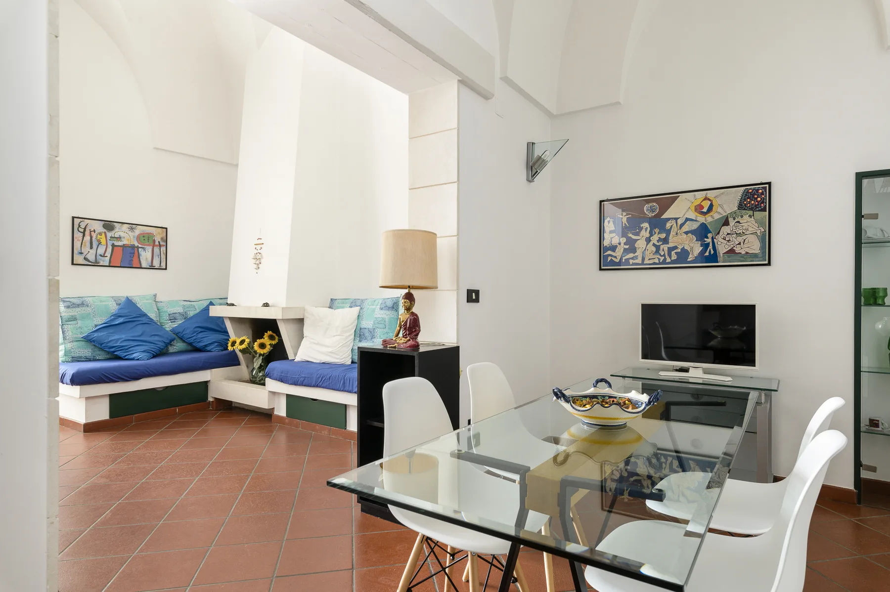 Una luminosa sala de estar y comedor con asientos empotrados y una mesa de cristal.