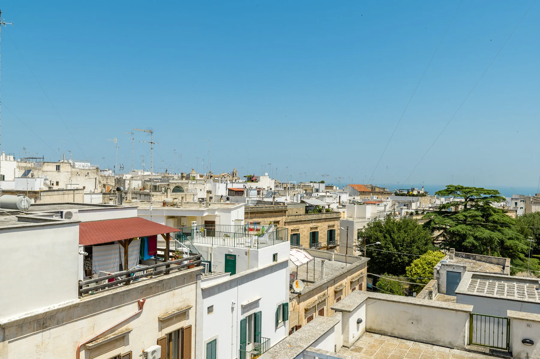 Vista desde una azotea sobre un pueblo costero, con edificios bajos y el mar en el horizonte.