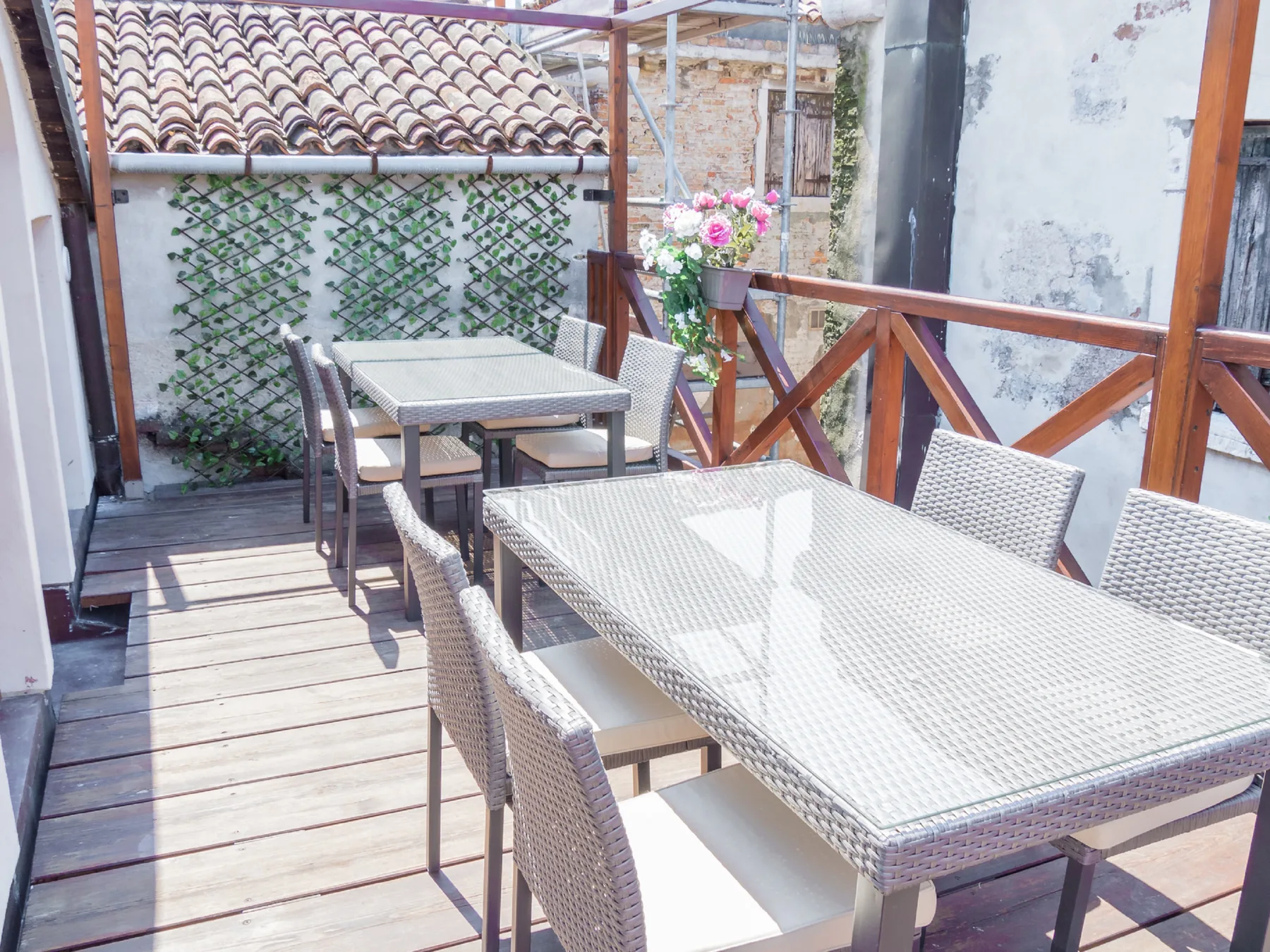 An outdoor patio with woven tables and seating beside a wooden railing.
