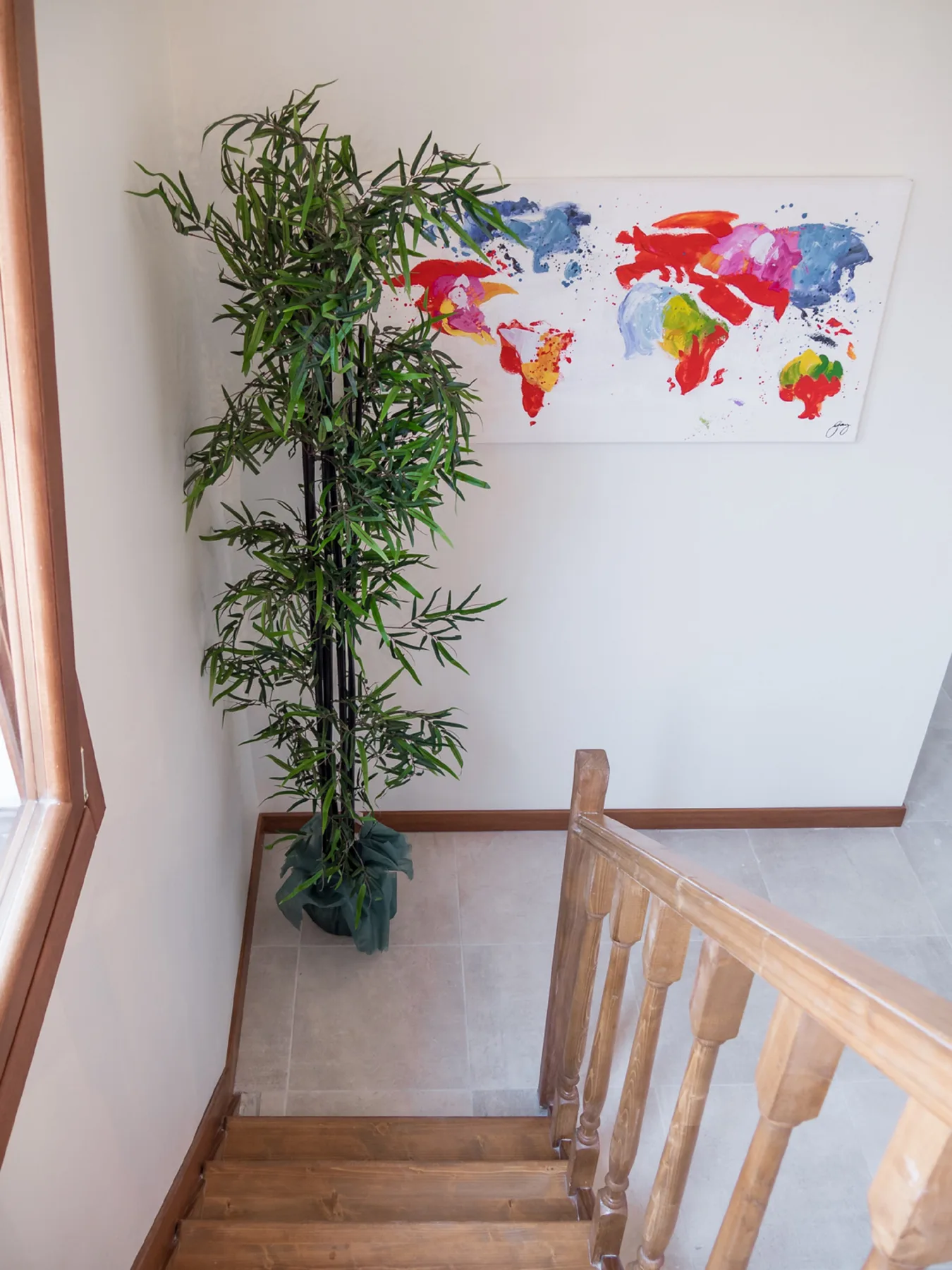 A stairwell with wooden steps, a potted plant, and a colorful world map on the wall.