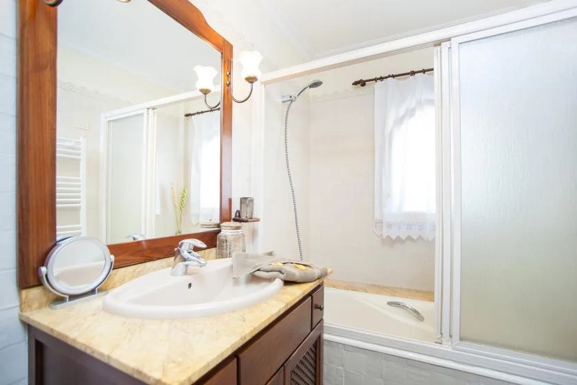 A bathroom with a sink, large mirror, and bathtub with a shower.