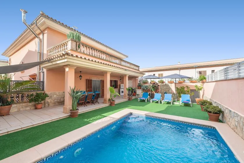A house and outdoor pool with patio seating and potted plants.