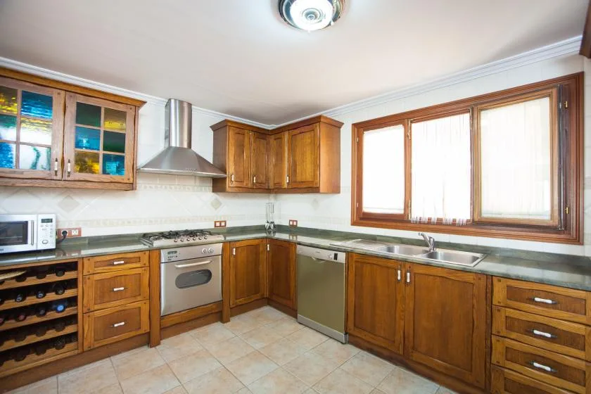 A kitchen with wooden cabinets, a cooking range, and a large window.
