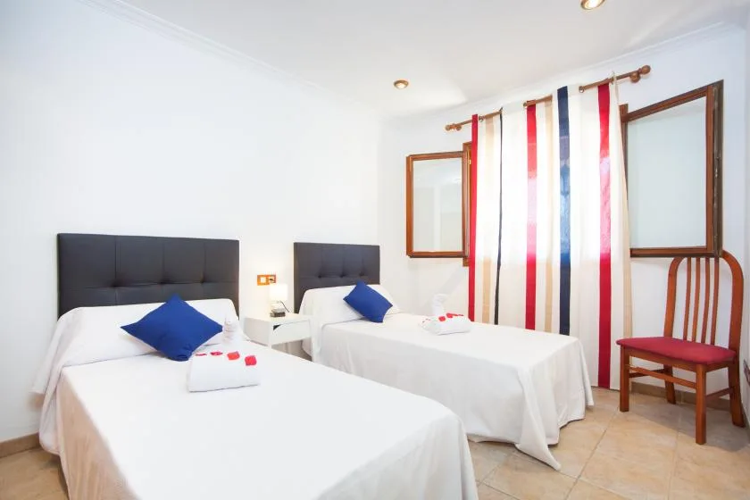 A bright bedroom with two beds and striped curtains.