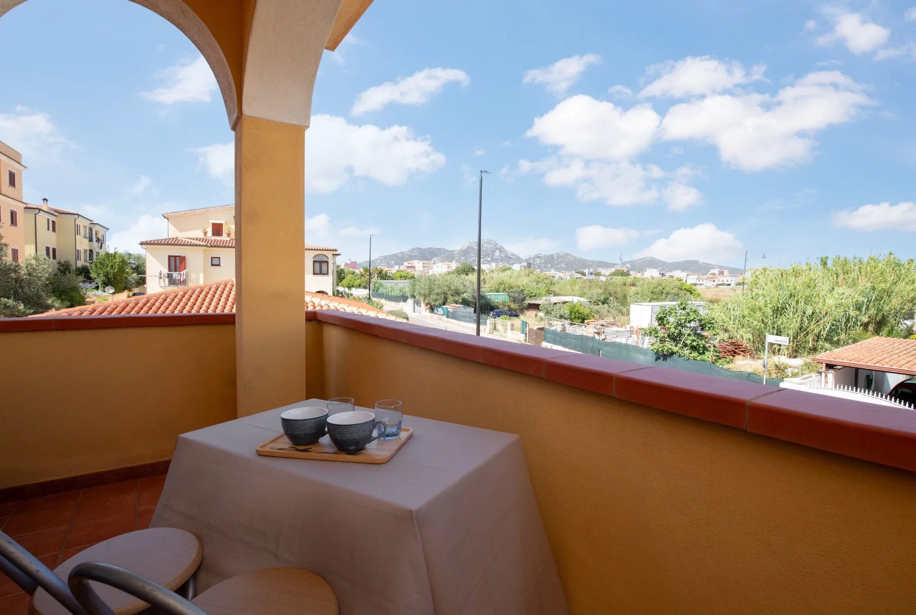 Una terraza cubierta con una mesa ofrece vistas de tejados y colinas lejanas.