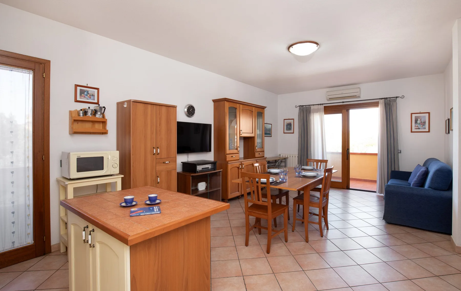 Una sala de estar y comedor amueblada, con una mesa de madera y asientos azules.